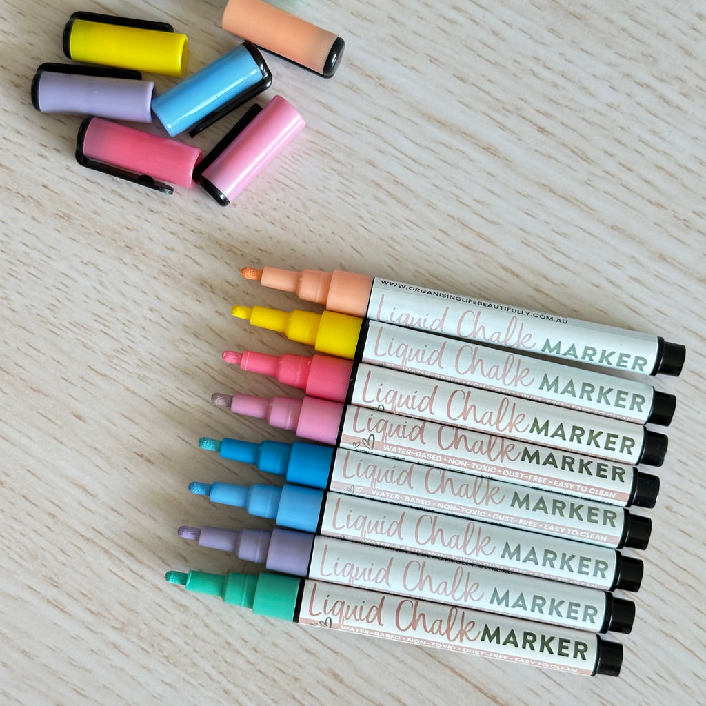 Pastel liquid chalk markers without caps on a wood background